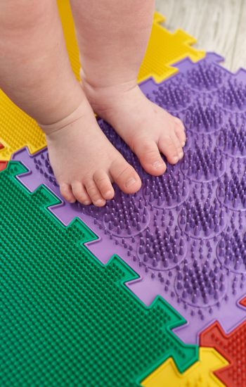 Foot massager. Kid walking on a orthopedic massage mat close up. Treatment and prevention of flat feet in children
